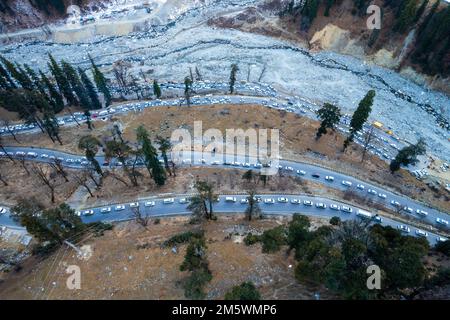 Luftdrohnenaufnahme von Autos, die in Staus auf der kurvenreichen Straße zum Atal Tunnel von Manali stehen, gefüllt mit Touristenfahrzeugen, die nach Schnee suchen Stockfoto