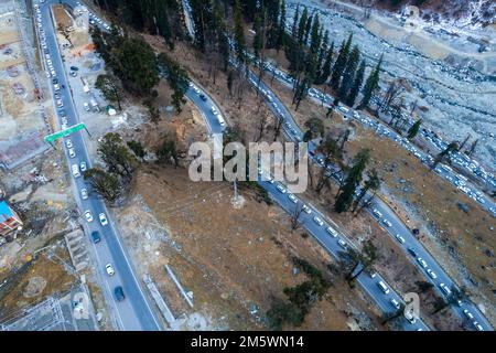 Luftdrohnenaufnahme von Autos, die in Staus auf der kurvenreichen Straße zum Atal Tunnel von Manali stehen, gefüllt mit Touristenfahrzeugen, die nach Schnee suchen Stockfoto