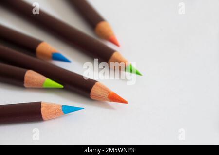 Ein Satz bunter künstlerischer Bleistifte. Leeres weißes Blatt Papier. Werkzeuge für Kreativität und Hobby. Foto für den Hintergrund. Platz für Text Stockfoto