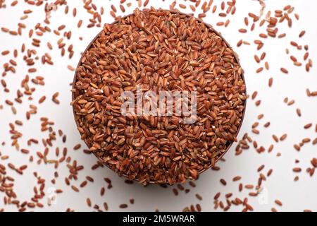 Trockener Reis in Holzschüssel. Langbraunreis Rotierend. Schließen. Die Körner fallen, und der Stapel wird gegossen. Weltkrise, Export, Import. Ernteprobleme, Sanktionen. In Stockfoto