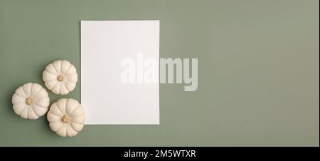 Leeres Blatt mit Halloween-Dekorationen auf pastellgrünem Hintergrund. Grußkarte, Einladungsmodell. Platz für die Beschriftung. Kürbis. Modernes Mini Stockfoto