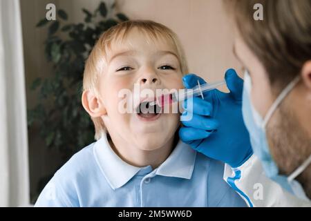 Der Junge bekommt Polio-Tropfen. Arztmachen zum Kind orale Schutzimpfung gegen Infektionen. Kleiner blonder Haarjunge im Krankenhaus. Kindergesundheitsfürsorge und Kinderkrankheiten Stockfoto