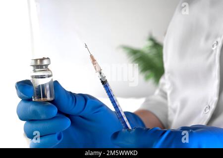 Krankenschwester hält eine Spritze und Impfstoffflasche in der Hand Nahaufnahme. Ein Arzt ist bereit, eine Injektion zu verabreichen. Wissenschaft. Medizinische Kosmetologie, Schönheitsbehandlung, Haut Stockfoto
