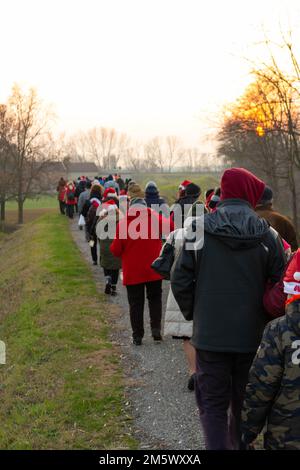 Zu Weihnachten gehen Sie in einer Gruppe von Personen an einem Böschungsfeld vorbei, Leintigione, Italien. Hochwertiges Foto Stockfoto