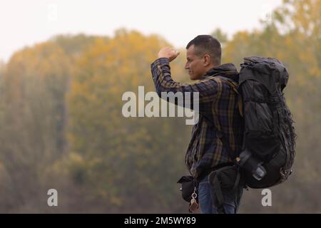 Porträt eines Reisenden am See im Herbst mit einer blau-grünen karierten Jacke. Hochwertiges Foto Stockfoto