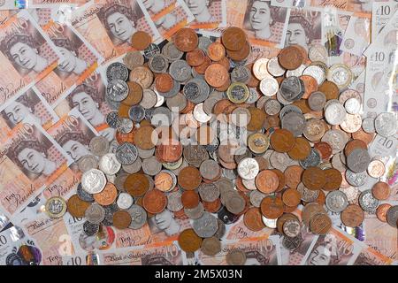 £10 Banknoten und ein Stapel britischer Münzen, einschließlich der Stückelungen of1p, 2p, 5p, 10p, 20p, 50p sowie £1 und £2 Münzen Stockfoto