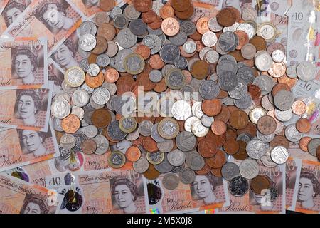 £10 Banknoten und ein Stapel britischer Münzen, einschließlich der Stückelungen of1p, 2p, 5p, 10p, 20p, 50p sowie £1 und £2 Münzen Stockfoto