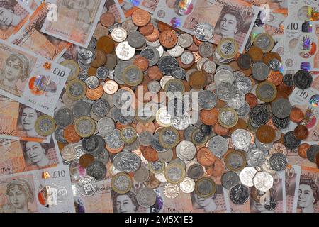 £10 Banknoten und ein Stapel britischer Münzen, einschließlich der Stückelungen of1p, 2p, 5p, 10p, 20p, 50p sowie £1 und £2 Münzen Stockfoto