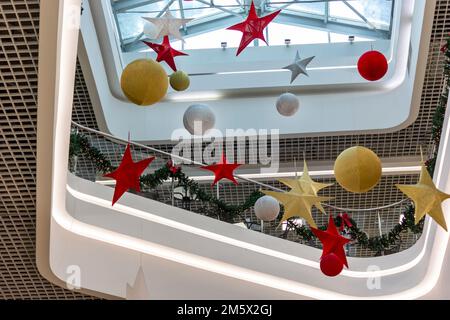 Neujahrsthema einer Weihnachtsgruß dekoriert mit roten Sternen und Kugeln, die hoch an der Decke hängen Stockfoto