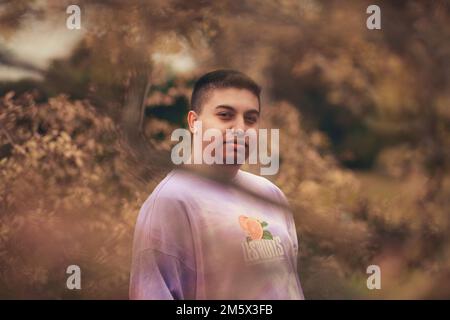 Ein junger spanischer Mann in einem lila Krawatten-Sweatshirt Stockfoto
