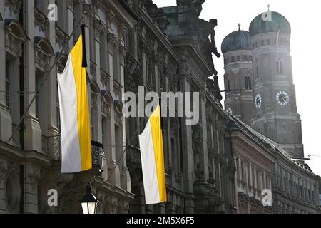 München, Deutschland. 31. Dezember 2022. Flaggen mit trauernden Flaggen hängen vor der offiziellen Residenz von Kardinal Reinhard Marx. Im Hintergrund sehen Sie die Türme der Frauenkirche. Papst Emeritus Benedict XVI. Starb am 31. Dezember 2022 im Vatikan, im Alter von 95 Jahren. Kredit: Katrin Requadt/dpa/Alamy Live News Stockfoto