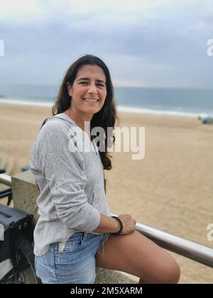 Ein Porträt einer schönen Frau mittleren Alters, die glücklich am Strand posiert. Stockfoto