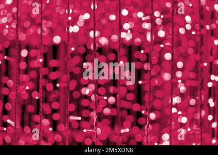 Festliche Weihnachtskulisse mit Lichtern und Bokeh. Strukturierter Vollformat-Hintergrund. Farbton des Jahres 2023 Viva Magenta Stockfoto