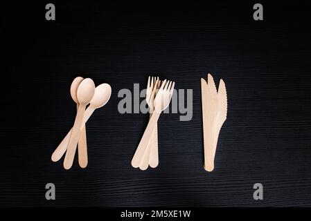 Umweltfreundliche Einweglöffel, Gabeln und Messer aus Holz auf dunklem Hintergrund Stockfoto