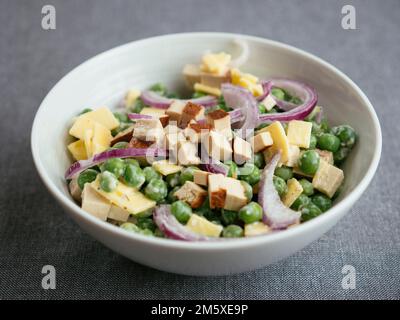 Veganer Erbsensalat mit milchfreiem Käse und Smokey Tofu Stockfoto