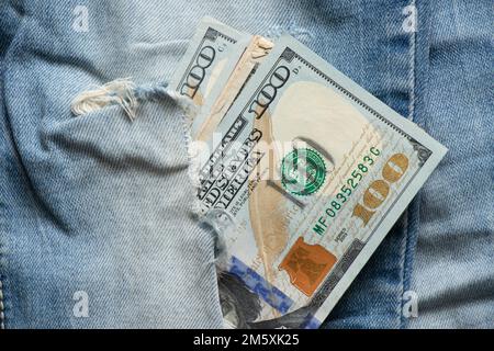 Amerikanische hundert Dollar, die aus einem Loch in Jeans-Nahaufnahme ragen Stockfoto