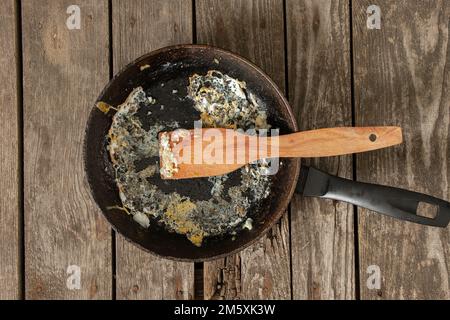 Bratpfanne mit Essensresten auf einem Holztisch nach dem Frühstück in der Küche zu Hause Stockfoto