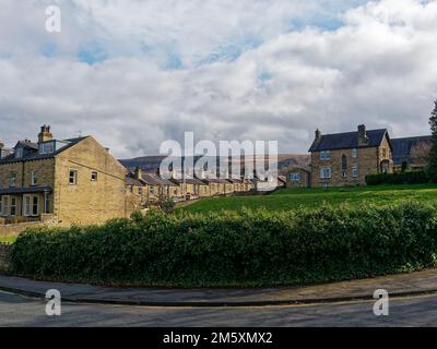 Einige der Steinhäuser und Terrassen in der Nähe von Ilkley Park und Riverside Gardens mit den Hügeln des Ilkley Moor in der Ferne. Stockfoto