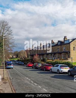 Terrassenförmige Steinhäuser mit Blick auf die River Wharfe am Ilkley Riverside Walk and Gardens, mit geparkten Autos auf der Straße, Stockfoto