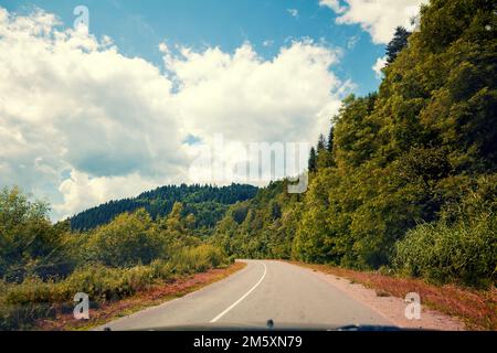 Blick auf die Bergstraße durch die Windschutzscheibe im Sommer. Karpaten. Ukraine Stockfoto