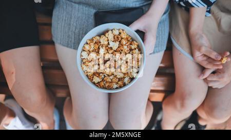 Freunde essen Popcorn auf der Straße. Nahaufnahme der Hände. Stockfoto