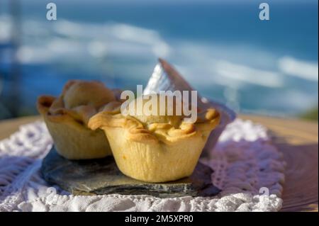 Portugiesische Gerichte, ofengebackene Hähnchenkuchen empada de Frango, serviert im Freien mit Blick auf den blauen, sonnigen Atlantik in der Nähe von Sintra im Raum Lissabon, Portugal Stockfoto