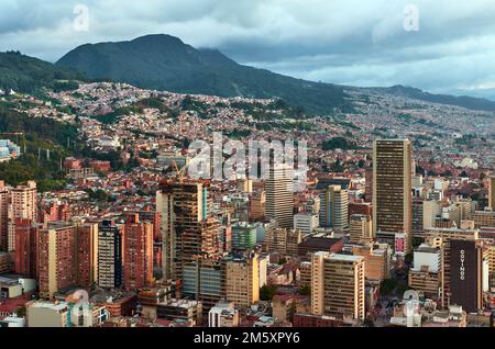 Blick auf das Zentrum der Stadt Bogota vom Gipfel des Torre Colpatria Tower, Kolumbien, mit Häusern und Bergen im Hintergrund unter bewölktem Himmel Stockfoto