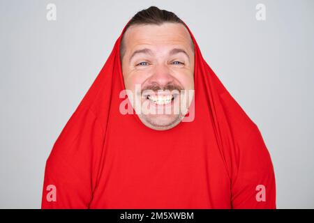 Ein witziger weißer Mann, der den Kopf mit einem Pullover bedeckt, der fröhlich und lustig lächelt. Stockfoto