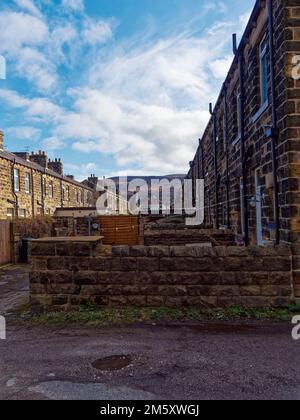 Gärten mit Steinhäusern in Profible Town in West Yorkshire mit Ilkley Moor im Hintergrund unter blauem Himmel. Stockfoto