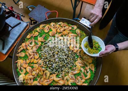 Große Paella-Pfanne mit Erbsen und Meeresfrüchten auf dem Herd Stockfoto