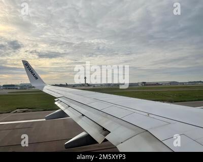 Flügel der Boeing 737 MAX auf der Landebahn bereit für Abflug am Flughafen London Standsted. Sonnenaufgang in dicken Wolken. Stockfoto