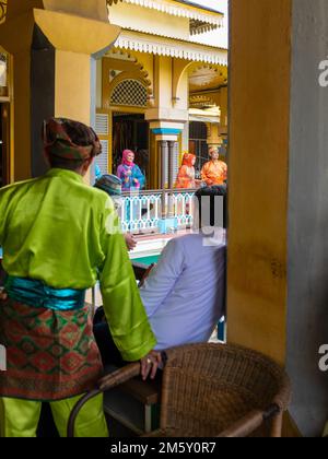 Medan, Indonesien - 21. Juli 2022: Vier Schauspieler, die in traditionellen Kleidungsstücken auftreten, werden von zwei Männern beobachtet, die auch in traditioneller Kleidung gekleidet sind. Vergeben Stockfoto