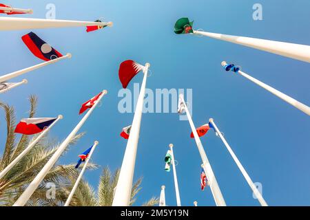 Flaggen verschiedener Länder der Welt flattern im Windhintergrund des blauen Himmels. Ansicht von unten nach oben. Hochwertige Fotos Stockfoto