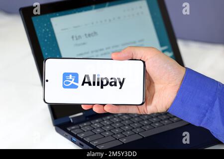 Alipay-Logo auf einem Smartphone vor einem Computer. Alipay 支付宝 ist ein digitaler Zahlungsdienst für mobile Geldbörsen mit Sitz in China. Stockfoto