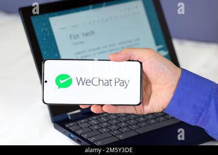 Logo von WeChat Pay auf einem Smartphone vor einem Computer. WeChat Pay 微信支付 ist ein digitaler Zahlungsdienst für mobile Geldbörsen mit Sitz in China. Stockfoto