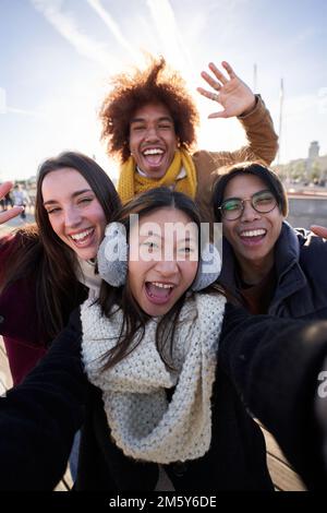 Vertikales Selfie einer Gruppe glücklicher Menschen, die Selfie-Fotos mit einem Telefon in Winterkleidung machen. Stockfoto