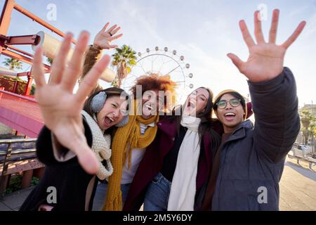 Vier fröhliche junge Freunde, die Selfie-Porträts in Winterkleidung machen. Glückliche Leute, die in die Kamera schauen Stockfoto