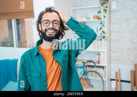Junger kreativer Unternehmer, der im modernen Home Office vor der Kamera lächelt Stockfoto
