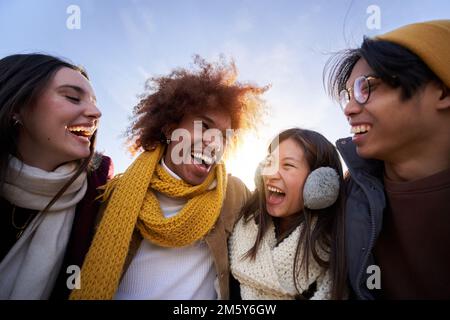 Multiethnische Gruppe von Freunden, die sich umarmen und Spaß haben isolierte junge, lächelnde Menschen, die zusammen lachen Stockfoto