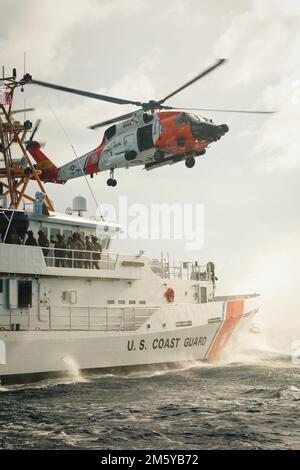 Eine Luftwaffenstützstelle der Küstenwache Clearwater MH-60 Jayhawk führt eine vertikale Evolution mit Mitgliedern der Küstenwache Cutter Valent und des Maritime Security Response Teams East am 24. Mai 2022 durch. Die vertikale Einfügung kann in einer Vielzahl von Boarding-Szenarien verwendet werden und stellt der Küstenwache ein zusätzliches taktisches Werkzeug zur Verfügung, das sie bei der Erfüllung von Strafverfolgungsmissionen einsetzen kann. (USA Küstenwache Foto von Petty Officer 1. Class Logan Kellogg) Stockfoto