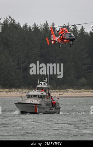 Eine Crew an Bord eines MH-65E Dolphin Helikopters vom Coast Guard Sector North Bend führt eine Aufzugsschulung mit einer Crew an Bord eines 47-Fuß-Motorrettungsboots von der Coast Guard Station Umpqua River durch, während sie in der Nähe von Winchester Bay, Oregon, am 14. März 2015 unterwegs ist. Flugbesatzungen trainieren regelmäßig mit Bereitschaftsbooten, um im Notfall kompetent zu bleiben. (USA Küstenwache Foto von Petty Officer Steve Strohmaier) Stockfoto