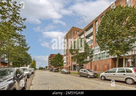 Eine Stadtstraße mit Autos, die an der Seite geparkt sind, und Gebäuden im Hintergrund, alle nach rechts ausgerichtet Stockfoto