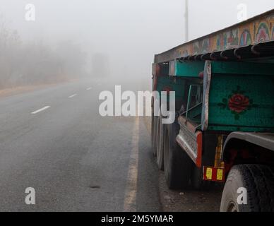 Anhänger in dickem Nebel auf einer Straße mit schlechter Sicht im Winter geparkt Stockfoto