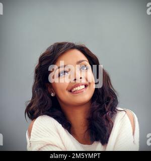 Oh, Freude. Studioaufnahme einer attraktiven jungen Frau, die vor grauem Hintergrund posiert. Stockfoto