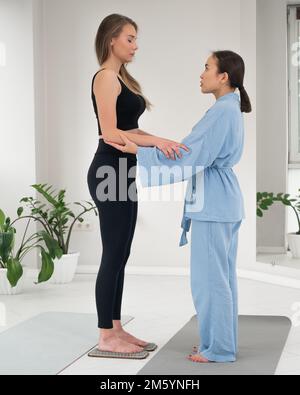 Weiße Frau steht auf Sadhu-Brettern mit Therapeuten-Unterstützung. Stockfoto