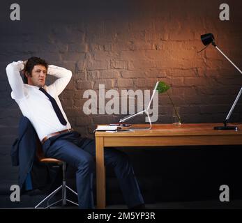 Große Träume erfordern harte Arbeit. Ein Geschäftsmann, der aufmerksam aussah, während er spät in der Nacht in seinem Büro saß. Stockfoto