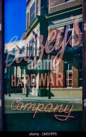 Historische Gebäude spiegeln sich im Fenster von Ellzey's Hardware vom 28. Dezember 2022 in Biloxi, Mississippi, wider. Stockfoto