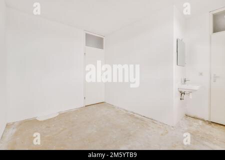 Ein leeres Zimmer mit weißen Wänden und keine Tür an der anderen Wand, aber es gibt eine Toilette darin Stockfoto