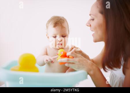 Sie genießt ihre neuen Badewannenspielzeuge. Ein kleines Mädchen, das Spaß in der Badewanne mit ihren neuen Spielzeugen hat. Stockfoto