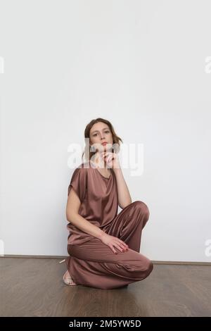 Studiofotos von jungen weiblichen Models im braunen Seidenkostüm-Set Stockfoto